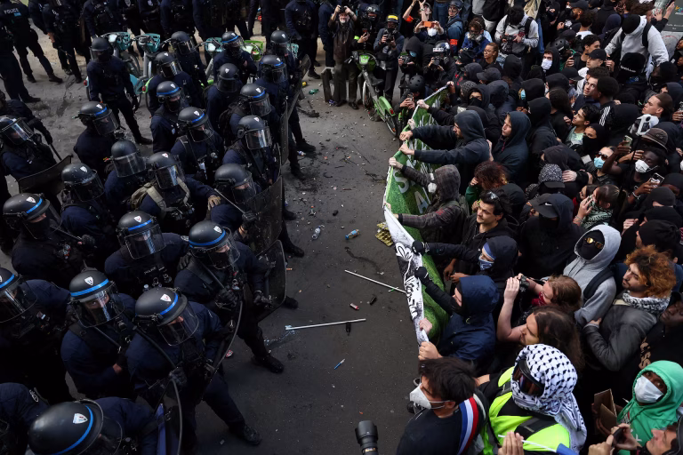 PARIS DEMONSTRATORS DEPLOY CLASSICAL MUSIC TO RESIST POLICE AND PROVOCATEUR VIOLENCE - IMAGE: Police officers in riot gear stand guard in front of protesters during a demonstration in Paris, October 8, 2026. REUTERS/Abdul Saboor